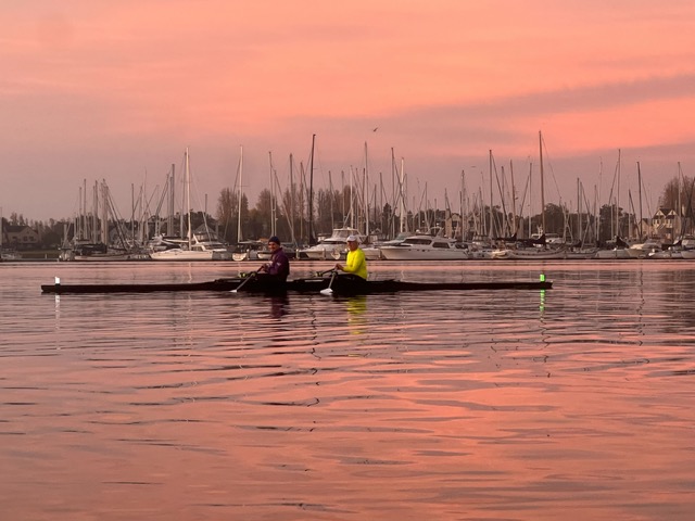 Rowers on the water at sunrise with estuary reflections